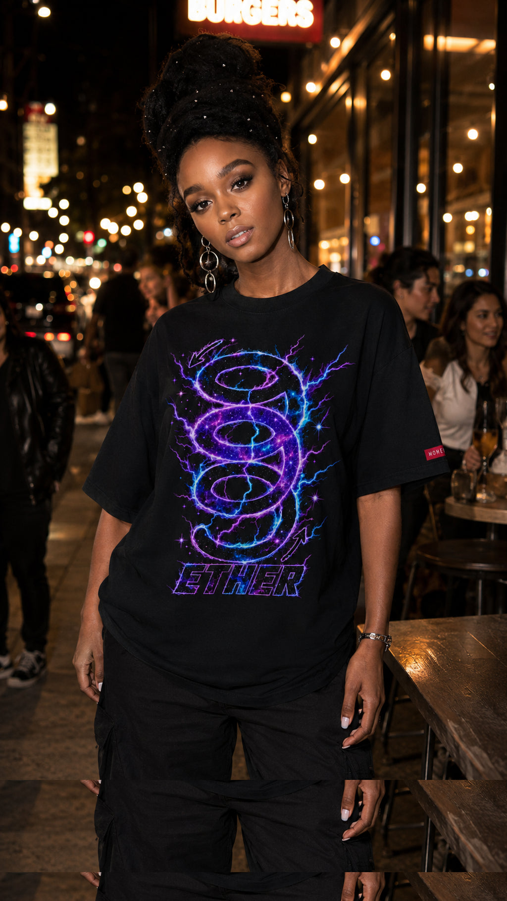 Woman wearing the black Nine (9) Ether Cosmic Energy Graphic Tee with a vibrant purple-and-blue neon design in a city at night.