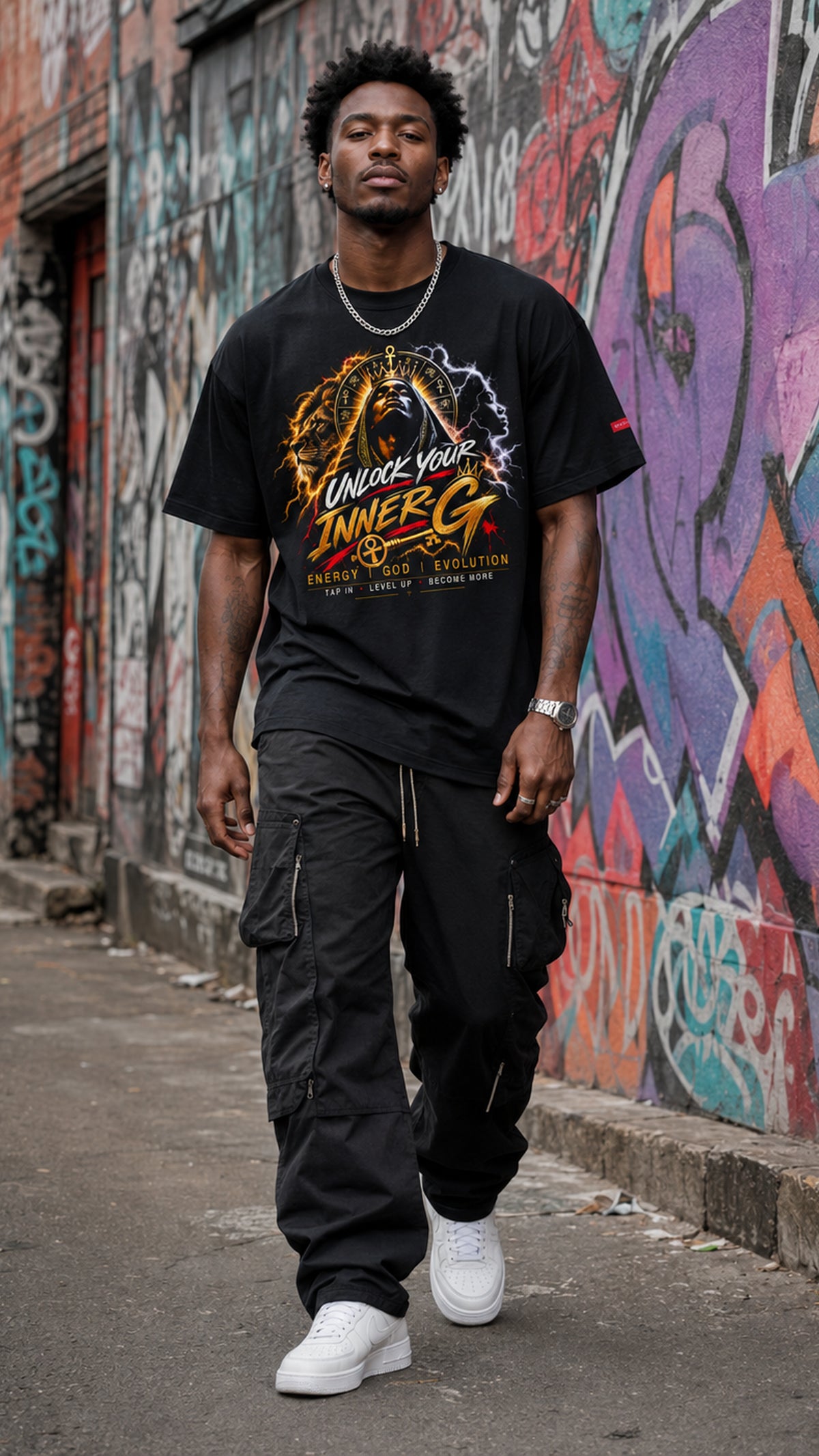 Man wearing the black Unlock Your Inner-G Graphic Tee with a yellow-and-orange design, walking along an urban street with colorful graffiti walls.